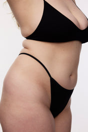 Model wearing black g-string, side view close-up