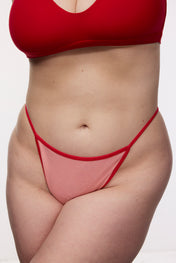 Plus size model wearing red g-string and bralette, front view