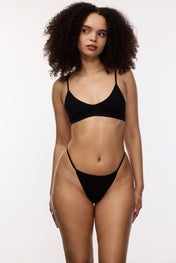 Model wearing black g-string and bralette, front view