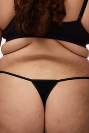 Plus size model wearing black g-string and bralette, back view